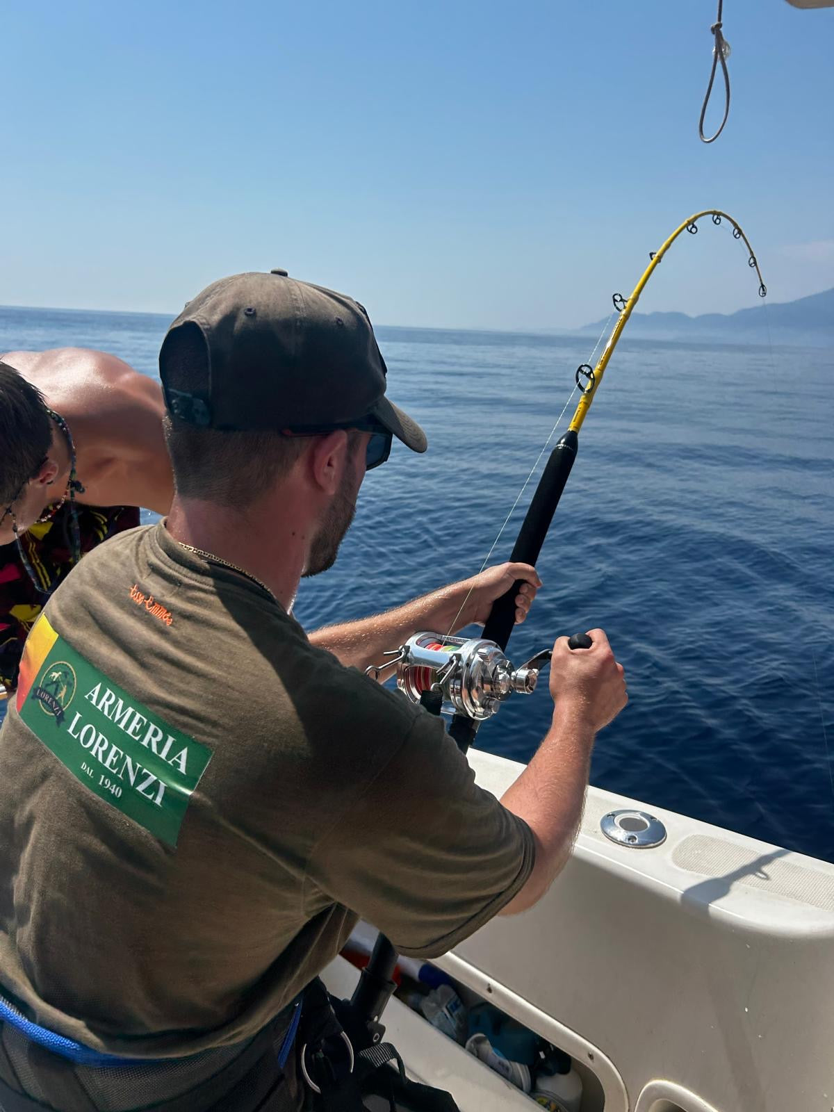 Pescatore in barca in azione con canna e mulinello, maglia Armeria Lorenzi 1940